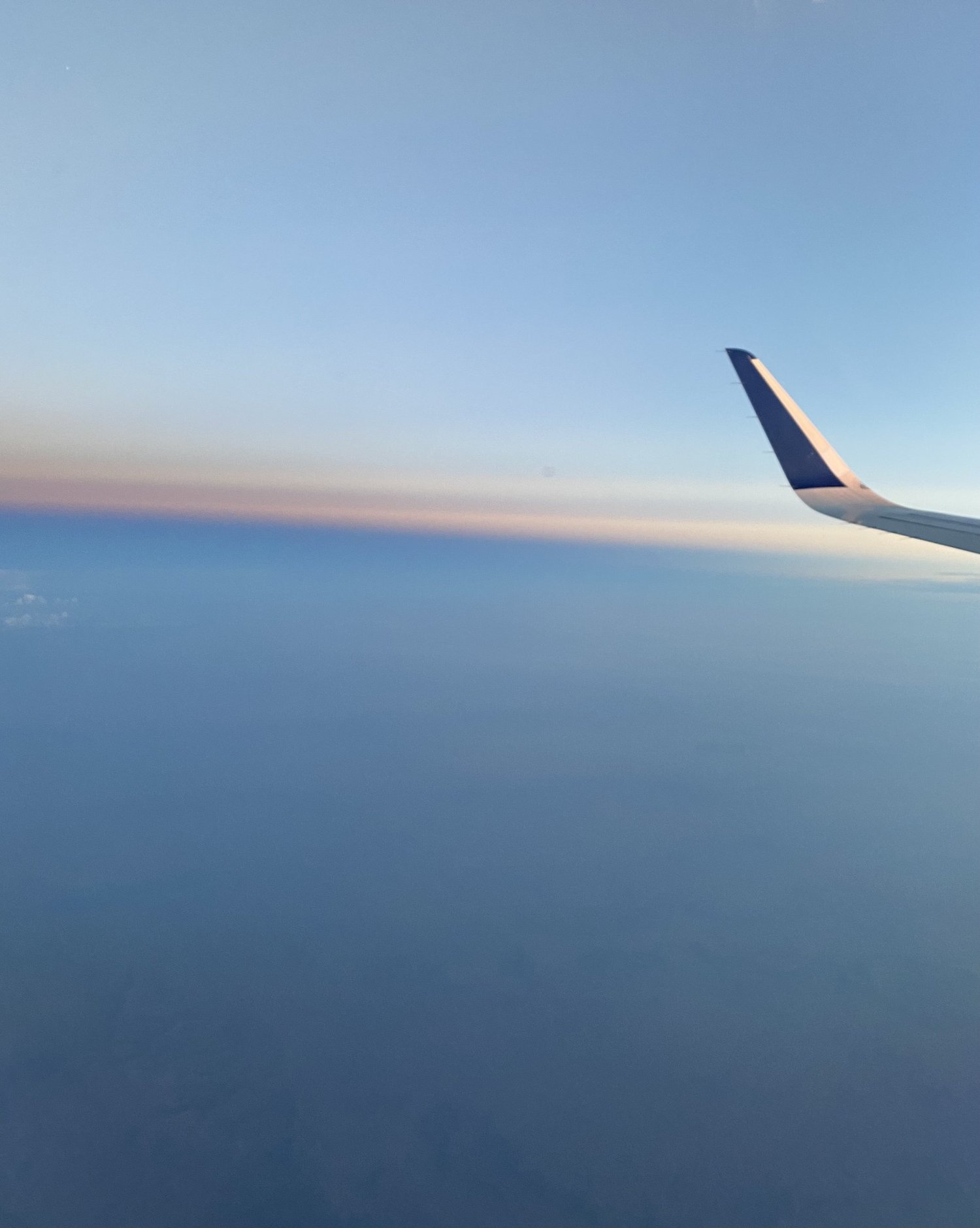 A view of the sky and airplane wing from a window seat